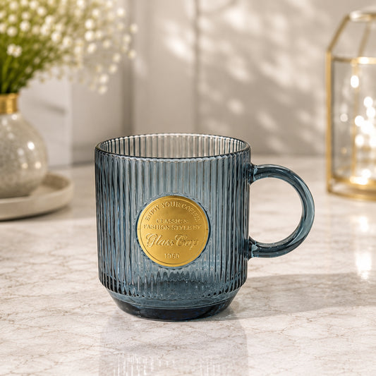 Dark blue ribbed Buck glass cup with handle and decorative gold-tone medallion